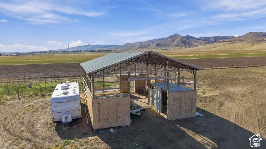 Open-frame structure with a metal roof, wood-sheathing siding, and mountain range backdrop