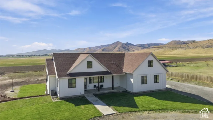 Two-story exterior with vertical siding, asphalt shingle roof, covered porch, and expansive mountain scenery
