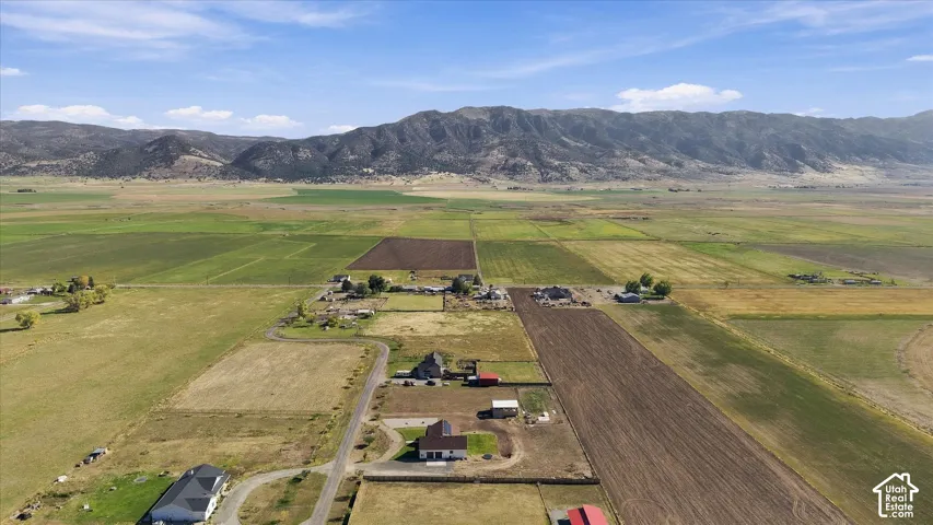 Aerial perspective featuring expansive acreage, cultivated agricultural fields, and a prominent mountain range backdrop