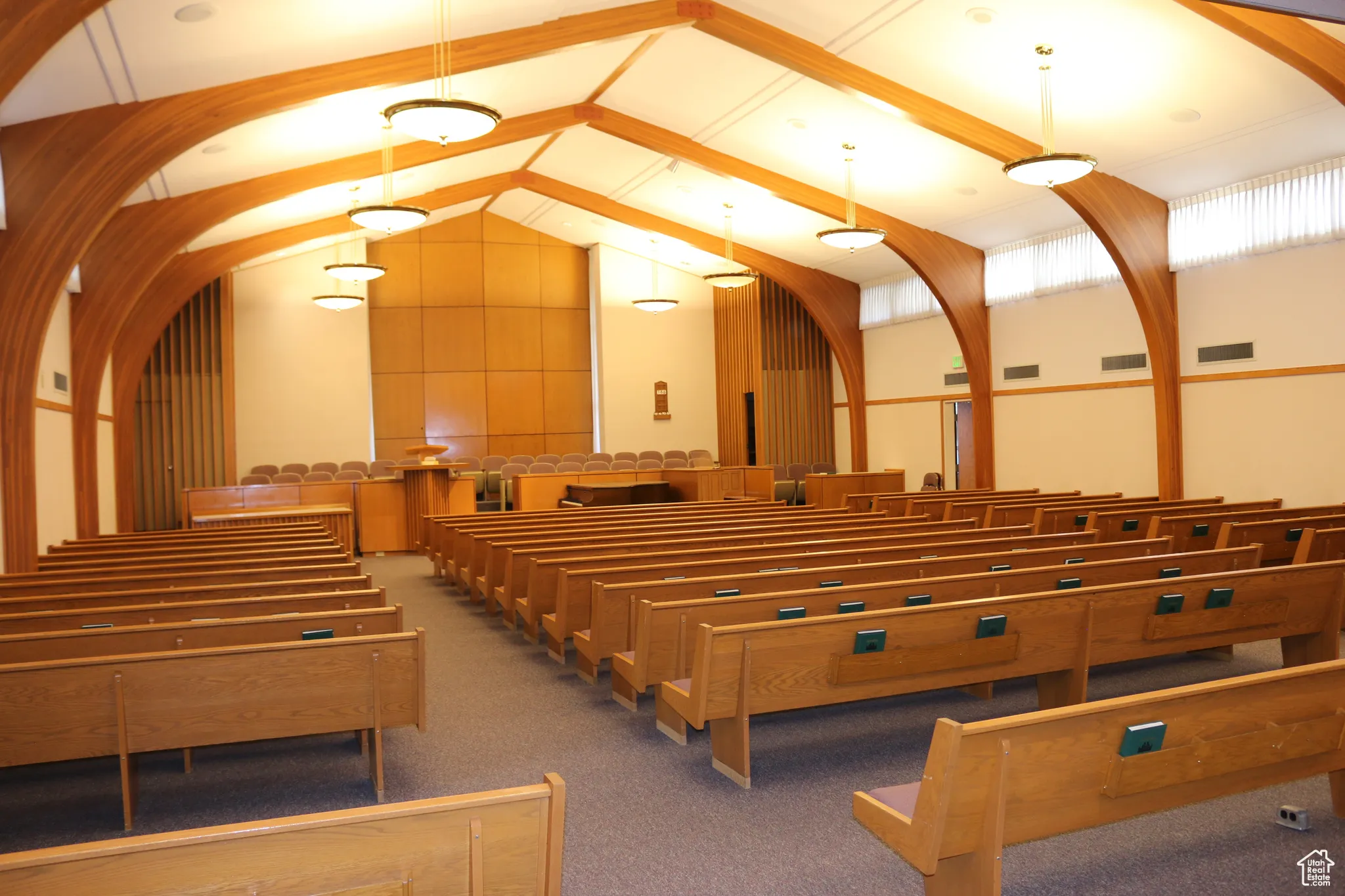 View of chapel with rows of wood pews and raised dais