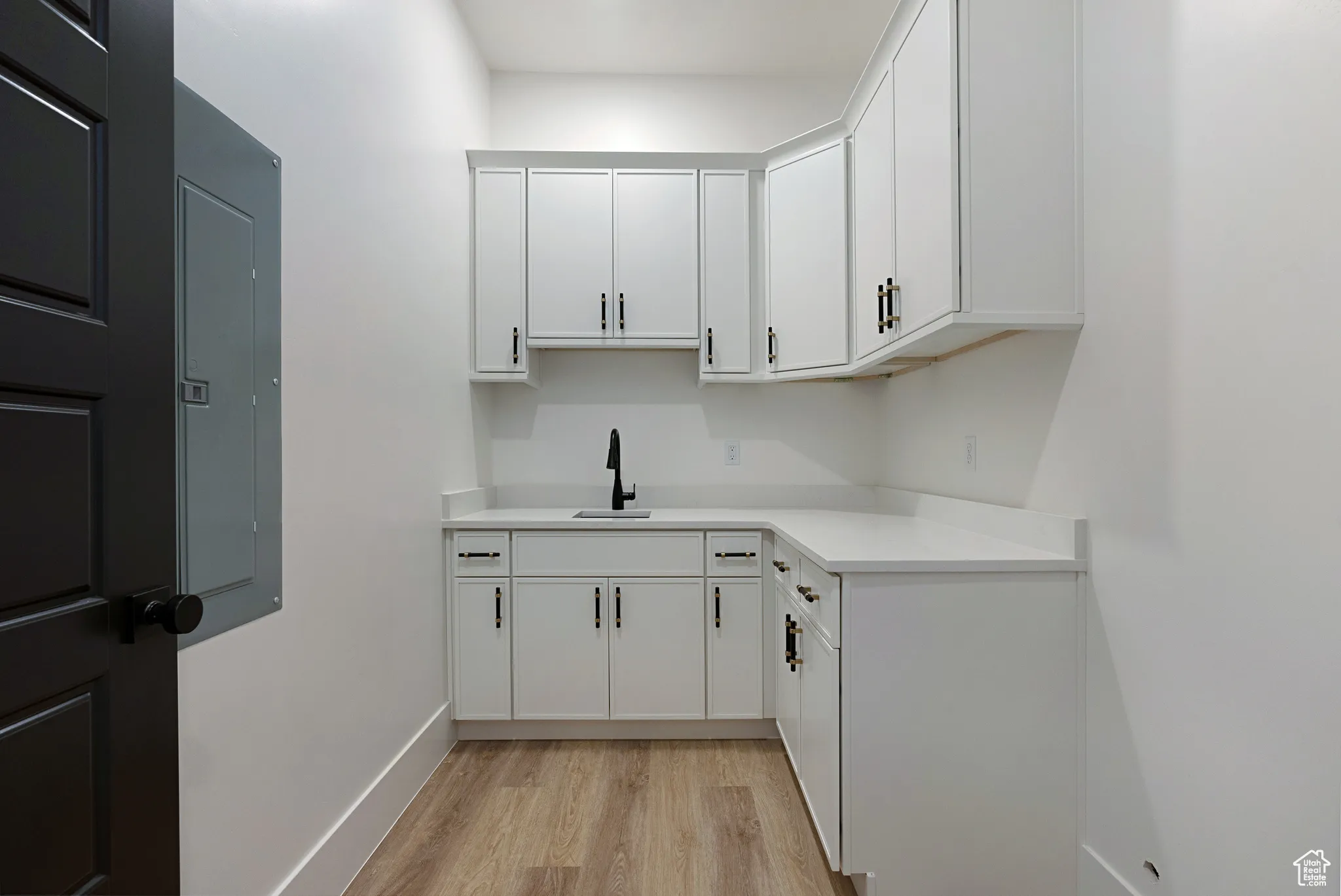 Kitchen featuring light wood-style flooring, light countertops, white cabinetry, and electric panel