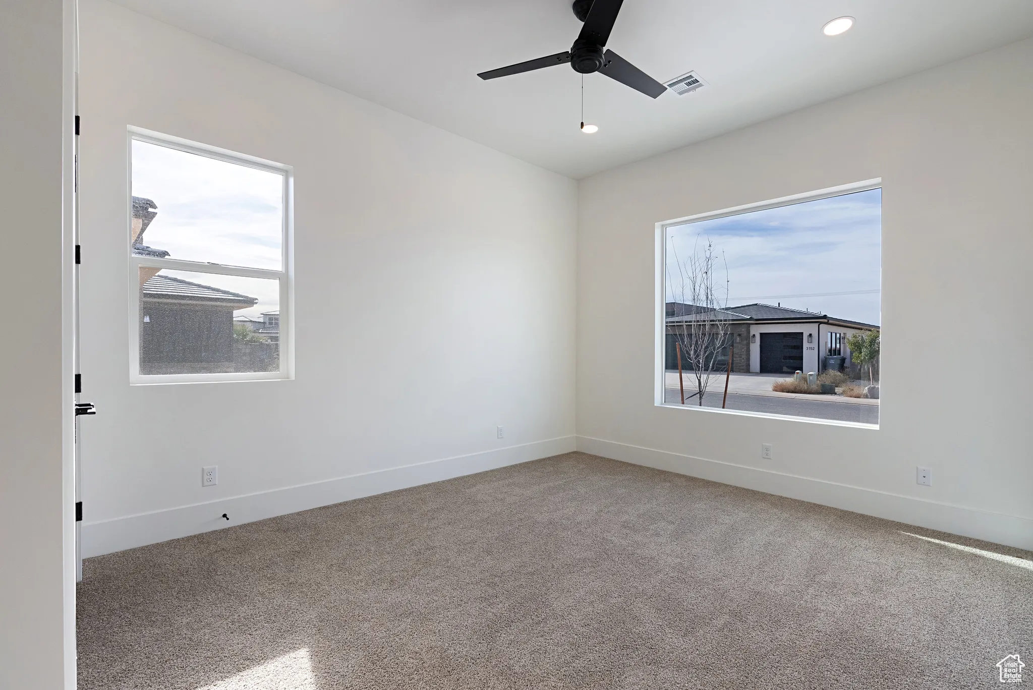 Empty room featuring plenty of natural light, ceiling fan, light colored carpet, and recessed lighting