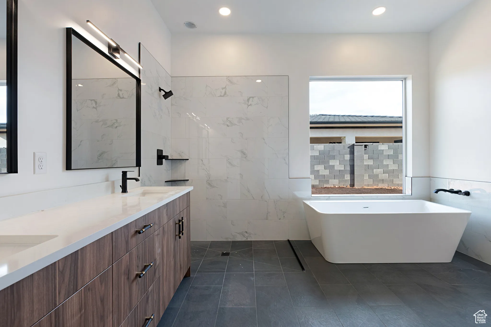 Bathroom featuring double vanity, a freestanding bath, tile walls, recessed lighting, and a tile shower