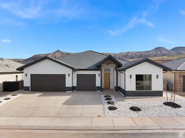 Modern farmhouse with board and batten siding, a garage, a mountain view, and concrete driveway