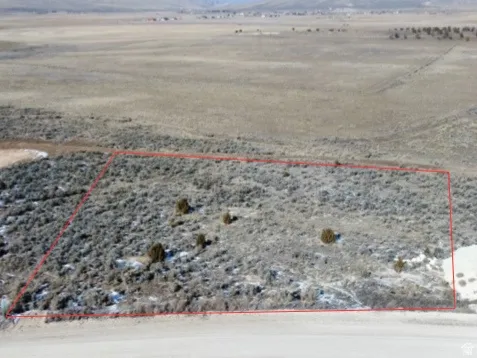 Aerial view of sparsely populated area with property parcel outlined and a mountain backdrop