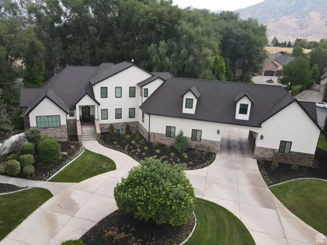 Modern inspired farmhouse with stucco siding, stone siding, concrete driveway, and a garage