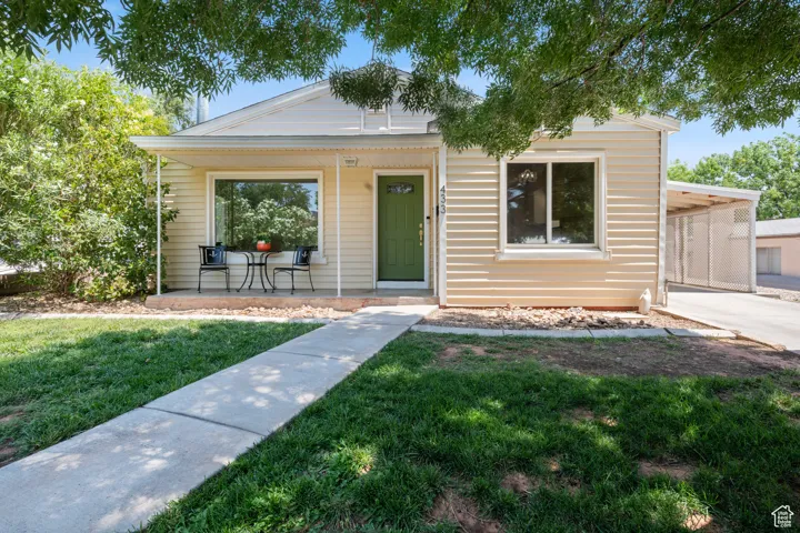 Bungalow-style house featuring a front lawn, a porch, and a carport
