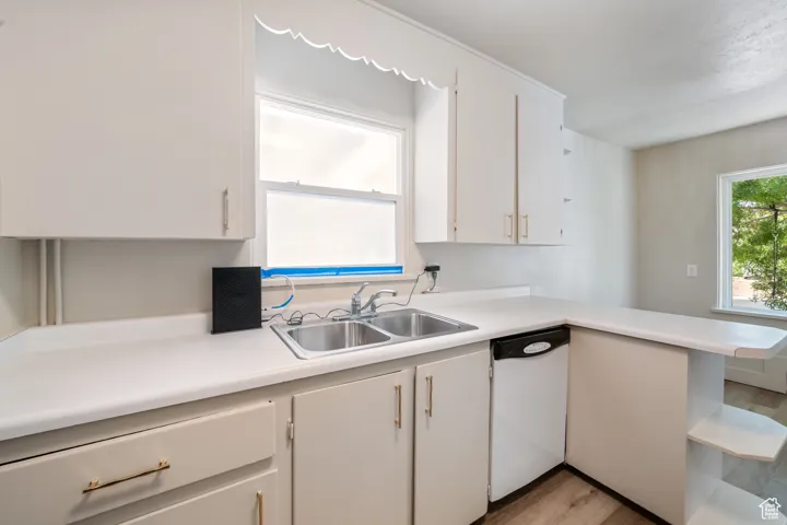 Kitchen featuring light countertops, white cabinets, white dishwasher, and light wood-style floors