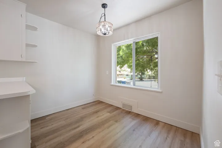 Unfurnished dining area with light wood finished floors and a chandelier
