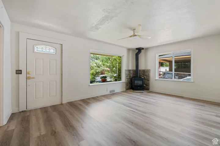 Foyer entrance featuring a wood stove, plenty of natural light, a ceiling fan, wood finished floors, and a textured ceiling