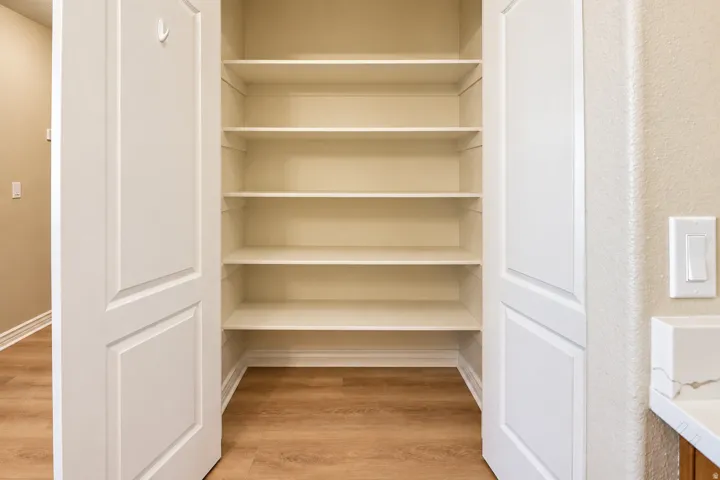Built-in shelving with multiple storage levels, wood-finish flooring, and panel doors