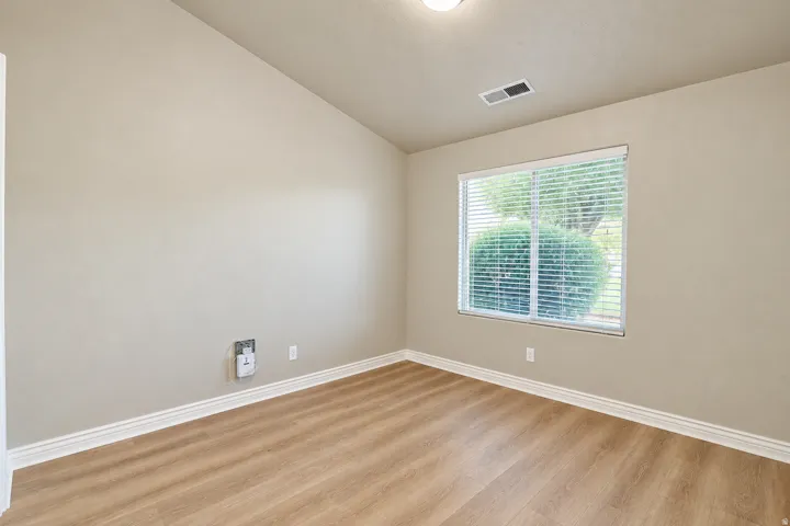 Wood-finish flooring, vaulted ceiling, recessed lighting, and a double-pane window with blinds