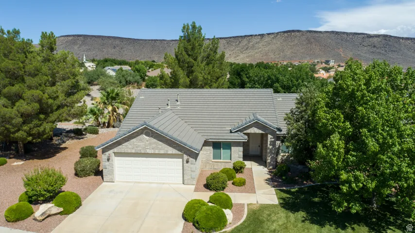 View of front of property with concrete driveway, a garage, a tile roof, a mountain view, and brick siding