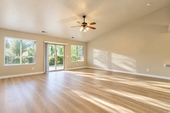 Vaulted ceiling, wood-finish flooring, ceiling fan, sliding glass door, multiple windows