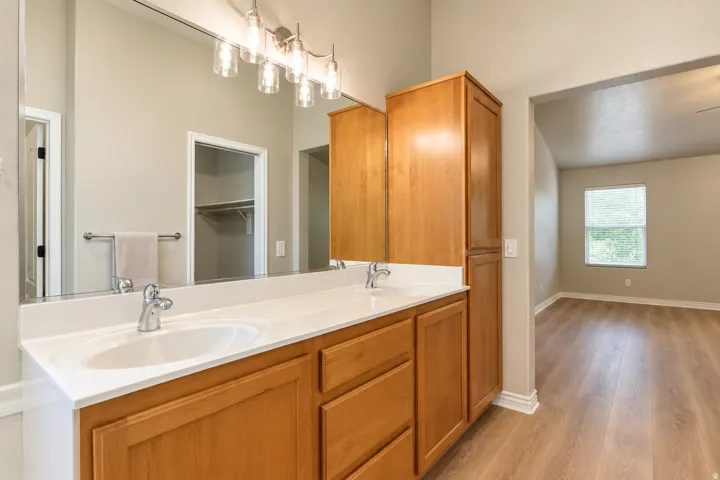 Dual vanity with an integrated countertop, wood-finish cabinetry, and overhead lighting