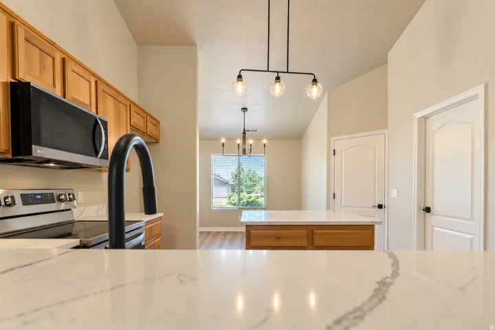 Kitchen featuring a white countertop with grey veining, integrated sink with a matte black faucet, stainless steel appliances, and wood-finish cabinetry