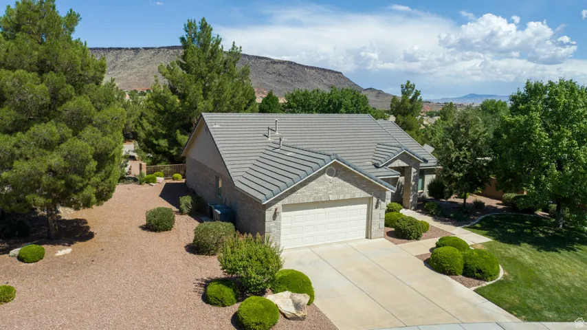 View of front facade featuring brick siding, an attached garage, concrete driveway, a mountain view, and a front yard