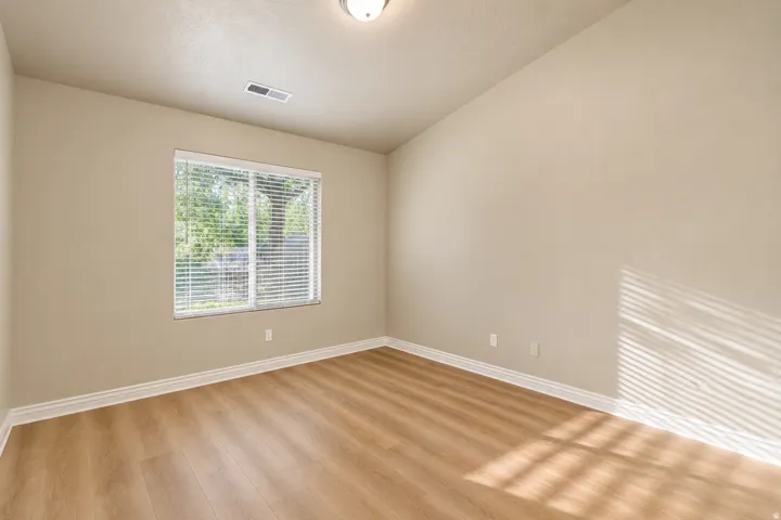 Sloped ceiling with recessed lighting, neutral wall palette, wood-finish flooring, and window with blinds