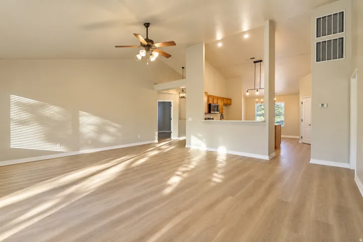 Vaulted ceilings, wood-finish flooring, ceiling fan, recessed lighting, and a breakfast bar