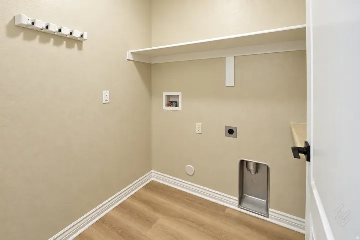 Laundry area featuring wood-finish flooring, a wall-mounted shelving unit, and a built-in hanging rack