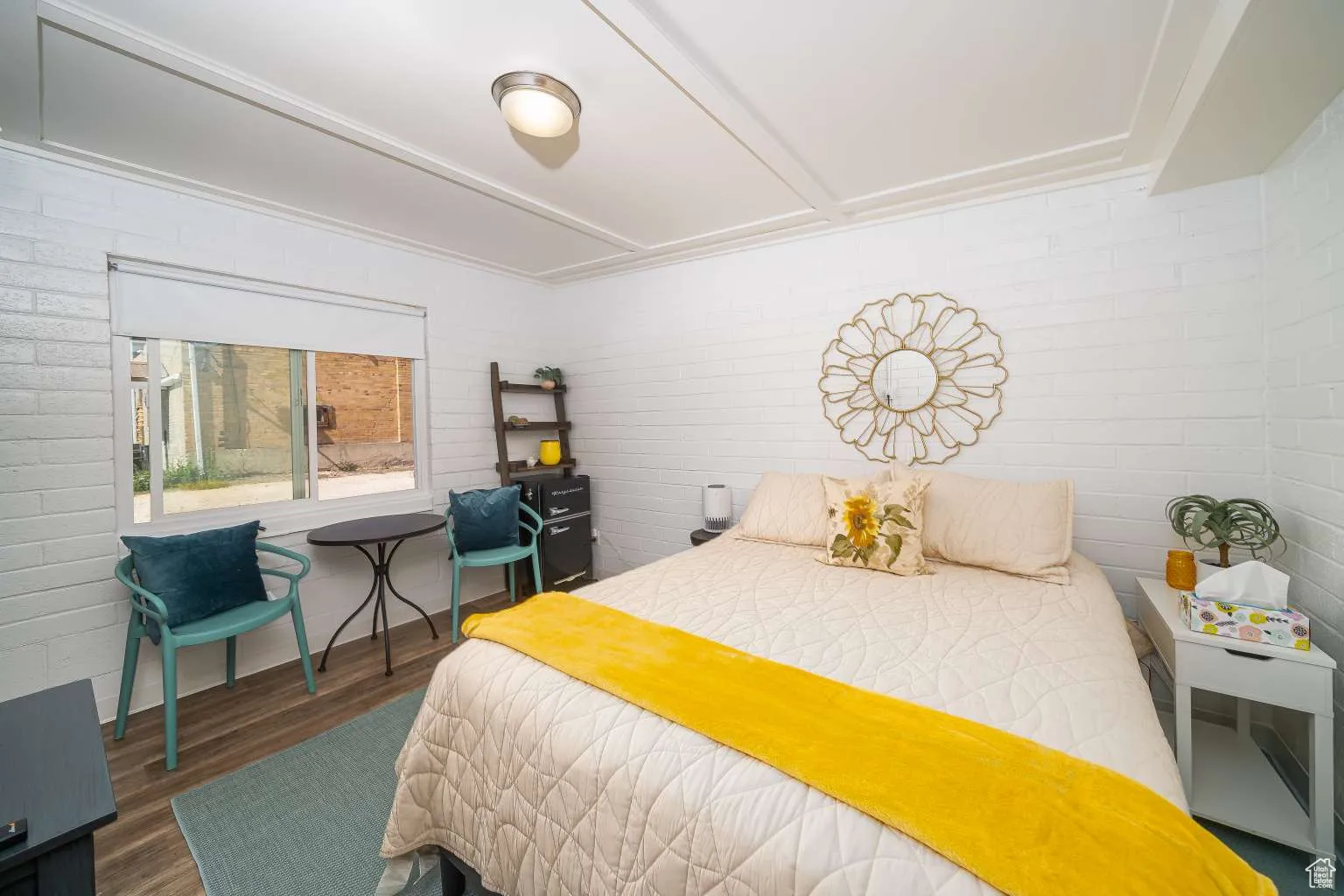 Bedroom featuring wood finished floors and brick wall