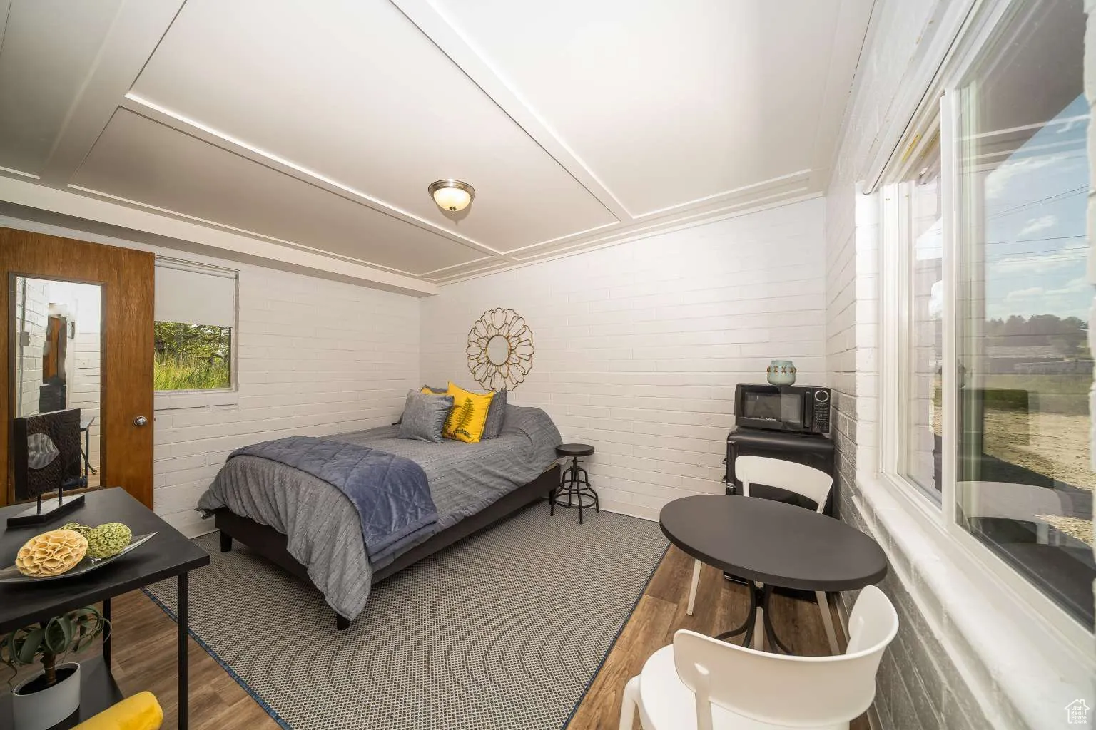 Bedroom with brick wall and wood finished floors