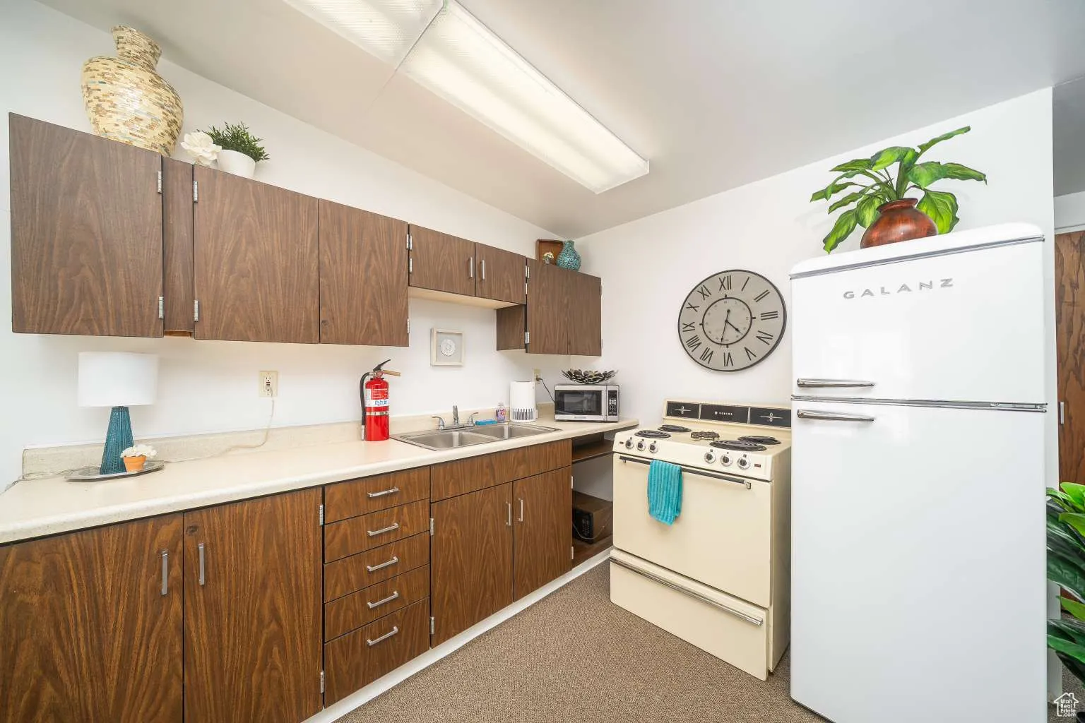 Kitchen featuring white appliances, vaulted ceiling, light countertops, and carpet floors