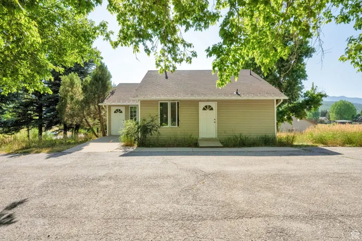 View of front of house featuring a garage, roof with shingles, and driveway