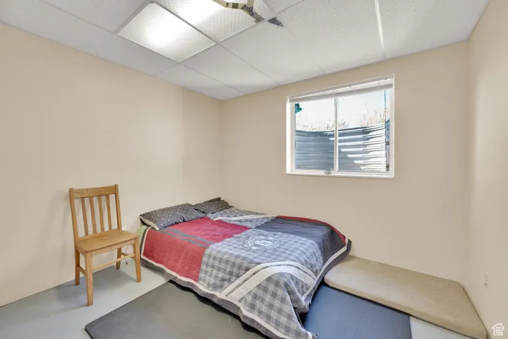 Bedroom featuring a paneled ceiling and finished concrete flooring