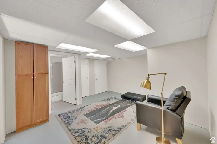 Sitting room with finished concrete flooring and a drop ceiling