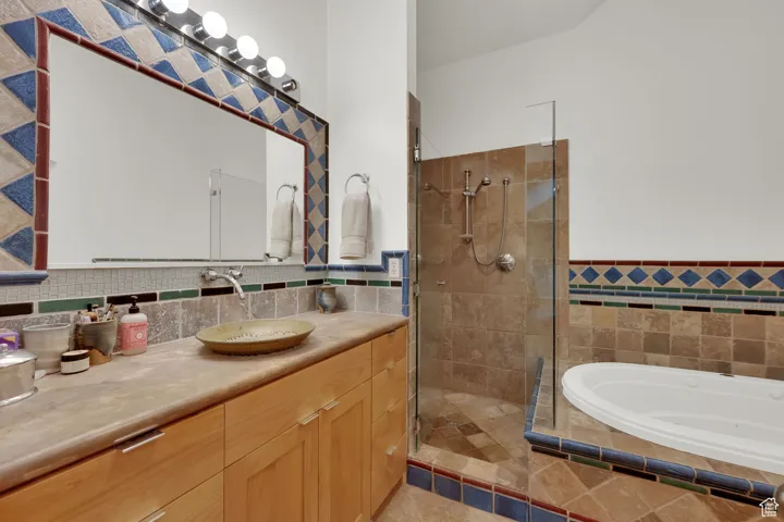 Full bath with vanity, tiled shower, tile walls, a garden tub, and a wainscoted wall