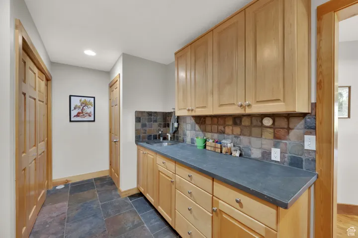 Kitchen featuring light brown cabinets, dark countertops, backsplash, and recessed lighting