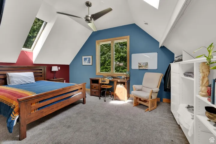 Bedroom with a skylight, carpet flooring, lofted ceiling, an office area, and ceiling fan