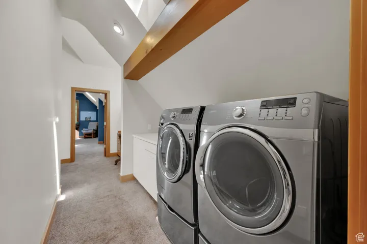 Laundry area with independent washer and dryer, light carpet, and cabinet space