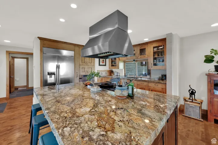 Kitchen featuring island range hood, stainless steel built in fridge, recessed lighting, light wood-style floors, and a large island