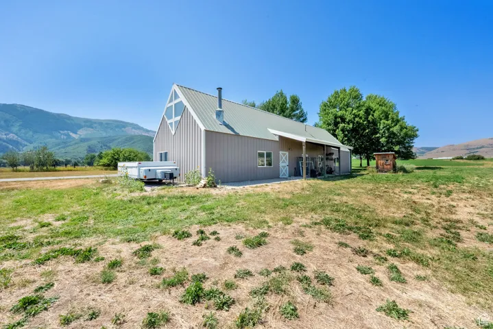 View of property exterior with an outdoor structure, a mountain view, a pole building, and a metal roof