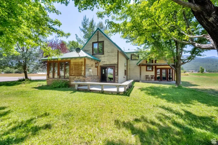 Back of property featuring a yard, stone siding, a metal roof, and french doors