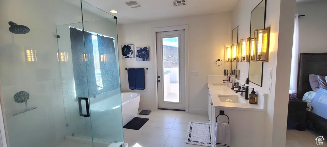 Bathroom with a stall shower, a freestanding bath, double vanity, ensuite bath, and light tile patterned floors