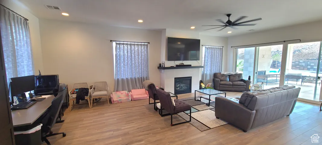 Living area with a tile fireplace, recessed lighting, light wood-style flooring, a ceiling fan, and a desk