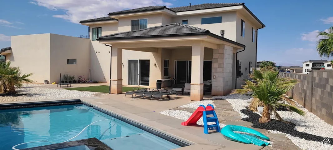 Rear view of property with a patio, stucco siding, and a pool with connected hot tub