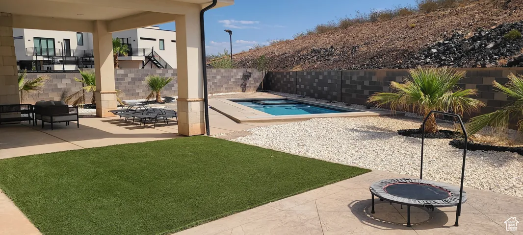 View of pool featuring a fenced backyard, a fire pit, a swimming pool, and a patio area