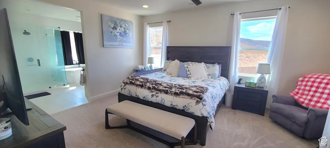 Bedroom featuring light colored carpet, ensuite bath, multiple windows, a ceiling fan, and recessed lighting