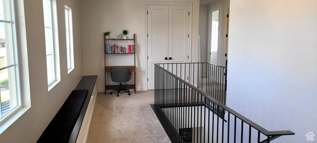 Office area with light carpet, plenty of natural light, and built in desk
