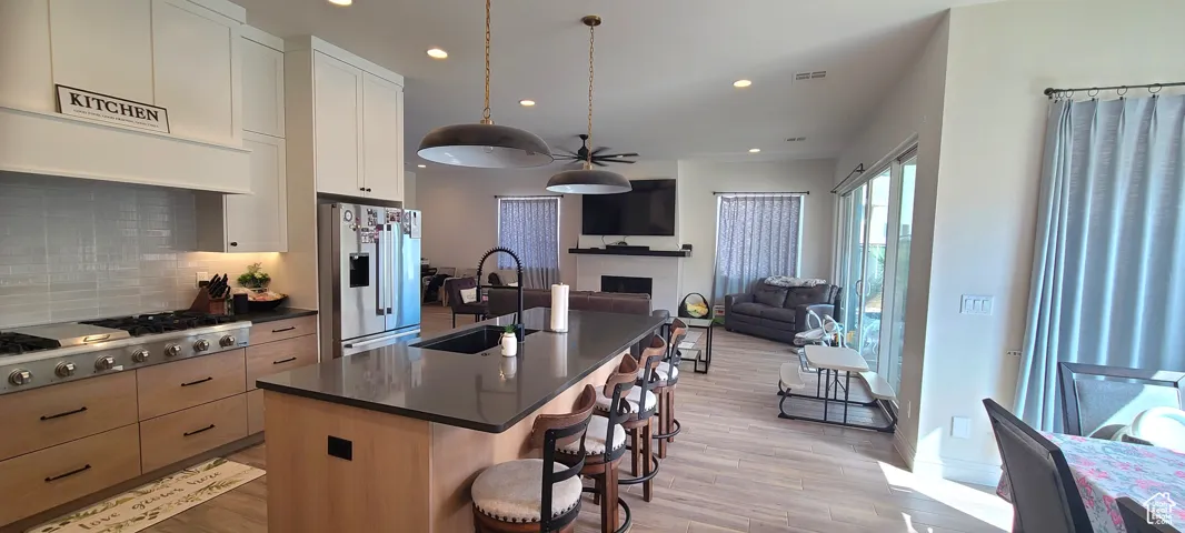 Kitchen with open floor plan, an island with sink, stainless steel appliances, tasteful backsplash, and recessed lighting