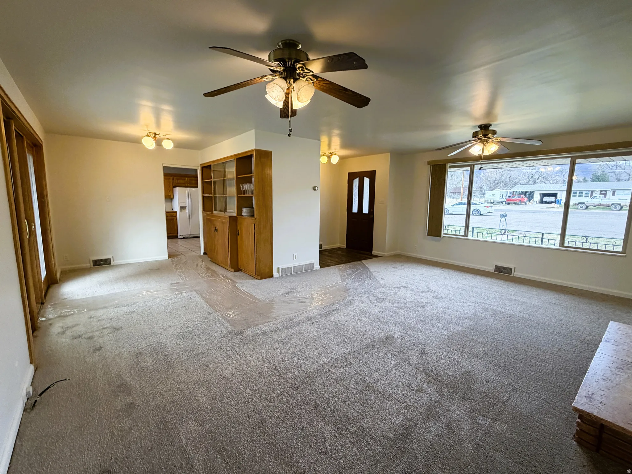 Unfurnished living room with carpet floors and ceiling fan