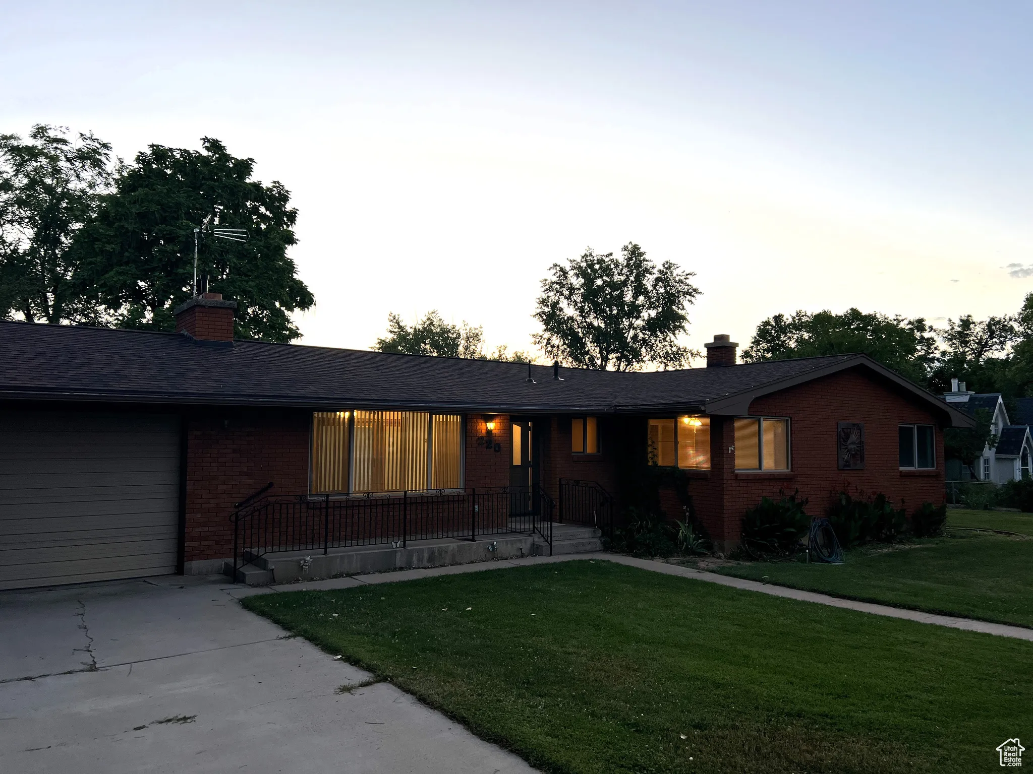 Ranch-style house with a chimney, a garage, a front yard, brick siding, and concrete driveway