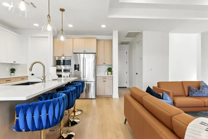 Kitchen with open floor plan, stainless steel appliances, recessed lighting, light wood-type flooring, and backsplash