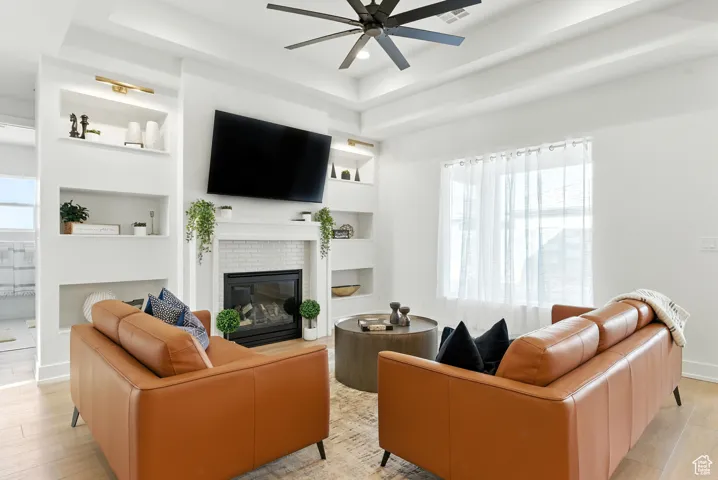 Living area featuring ceiling fan, built in features, a fireplace, light wood-style floors, and recessed lighting