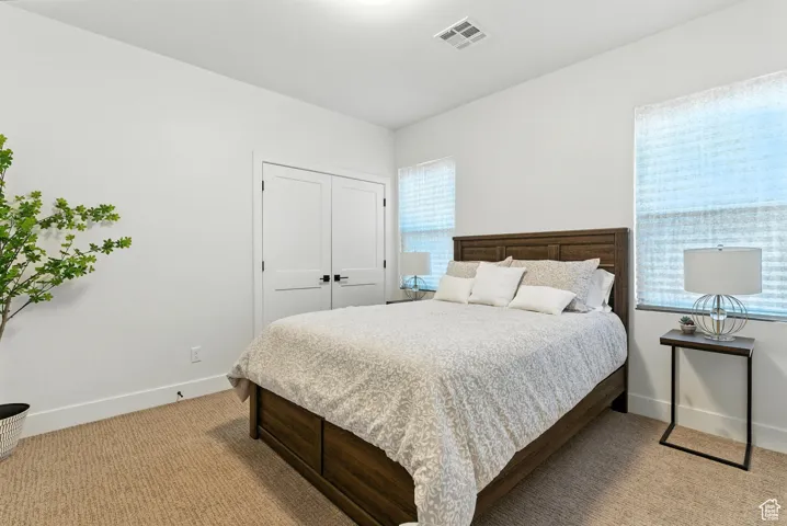 Bedroom with light carpet and a closet
