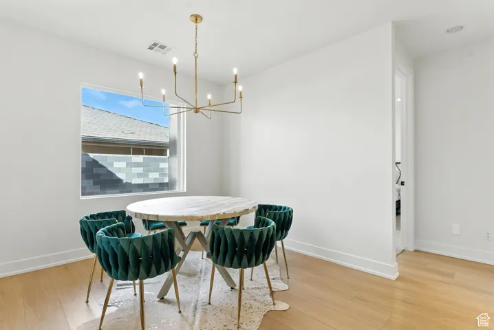 Dining area with light wood-type flooring and a chandelier